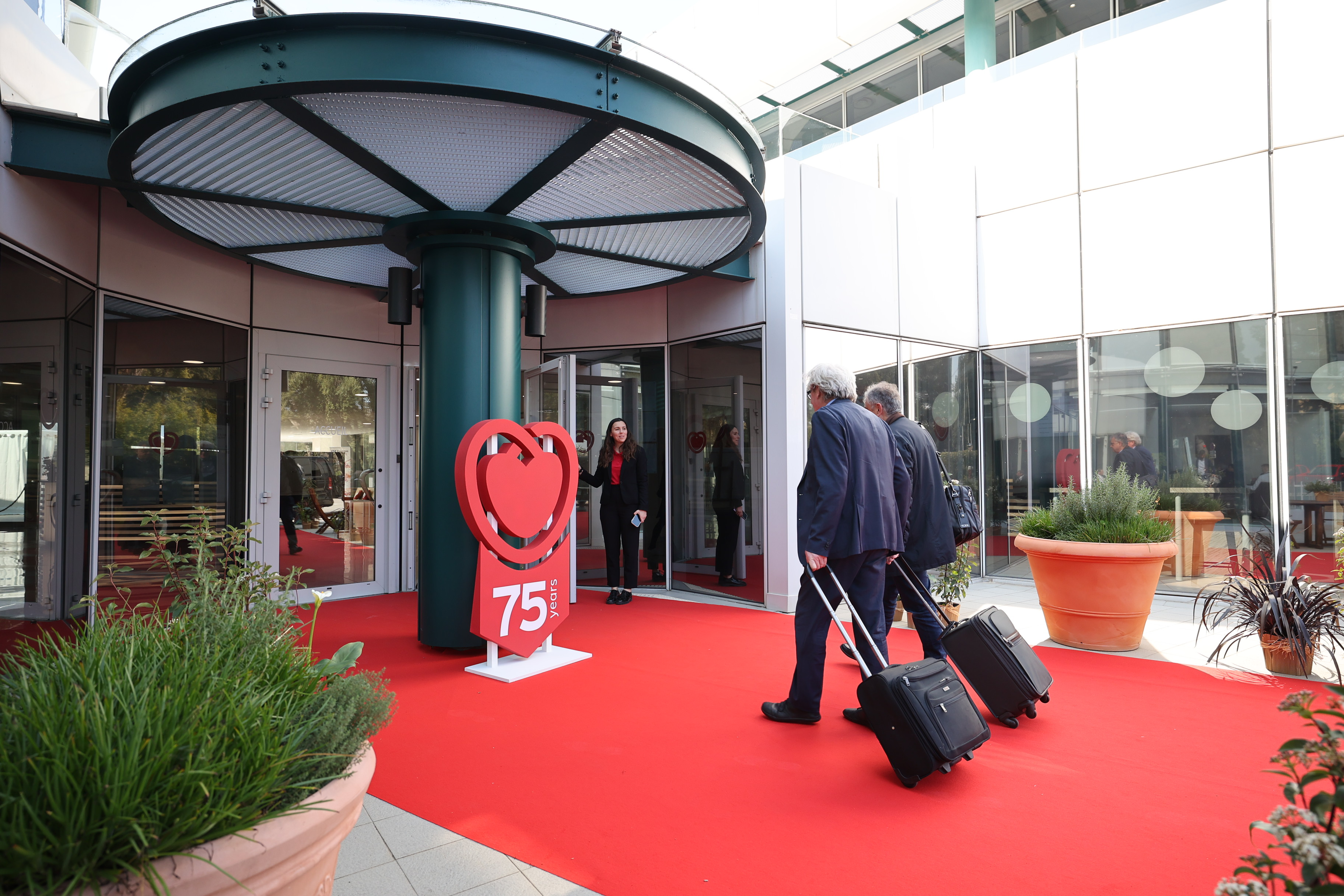 Two participants being greeted at building entrance